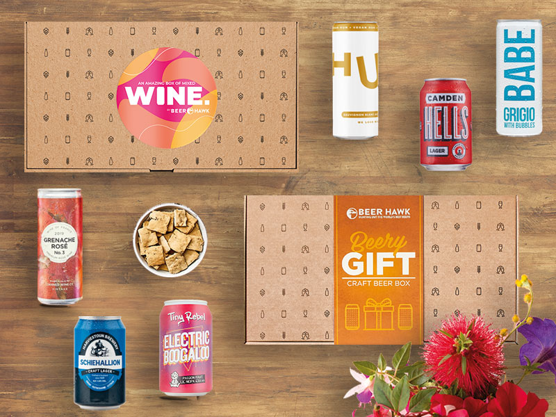Mother's Day Gift Ideas - Wooden Table Filled with Beer and Wine and Flowers in the Background